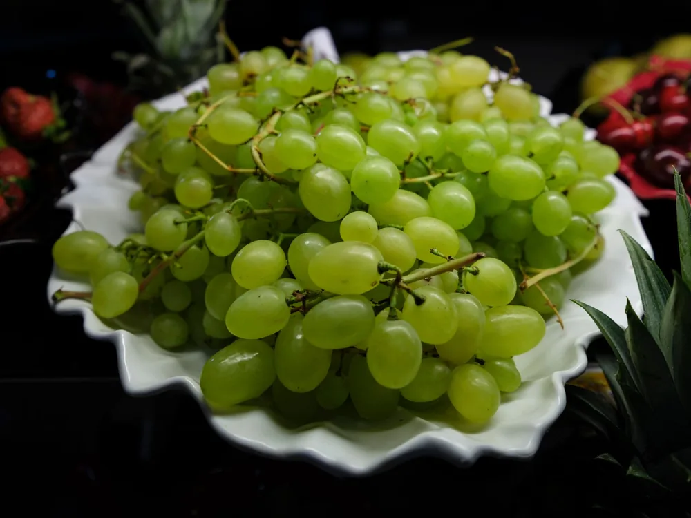 Fresh green grapes on a white plate, perfect for healthy food themes