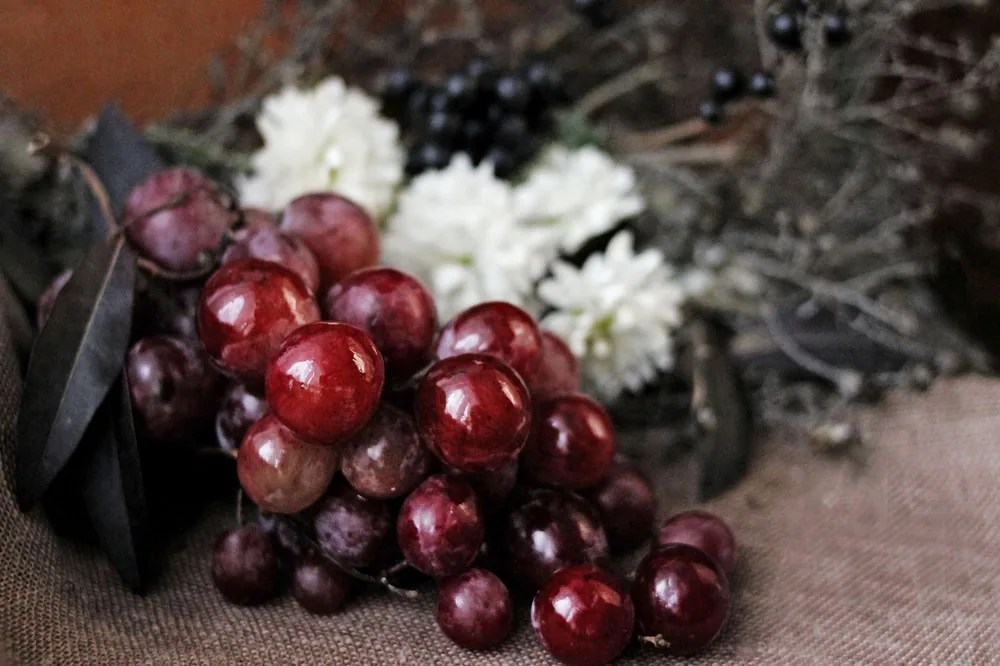 Fresh red grapes surrounded by flowers and foliage