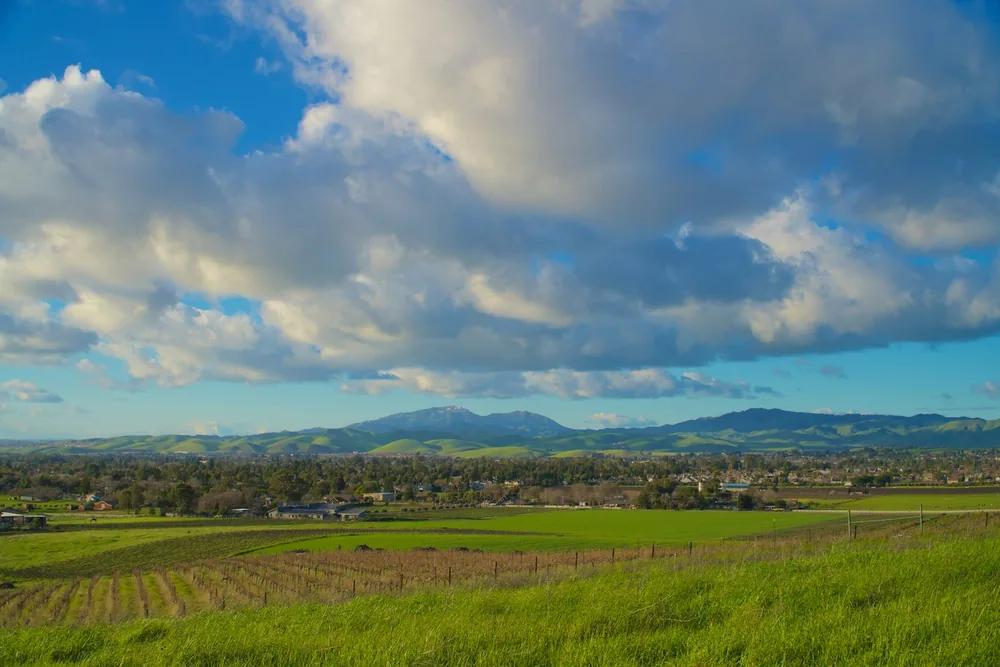 Green fields and distant hills under a cloudy sky