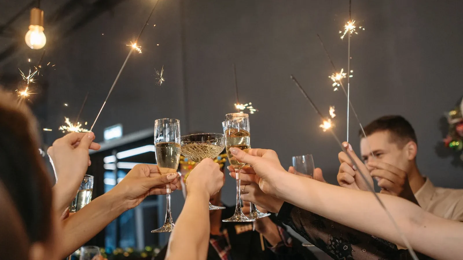 Group of adults celebrating with sparklers and toasting champagne indoors