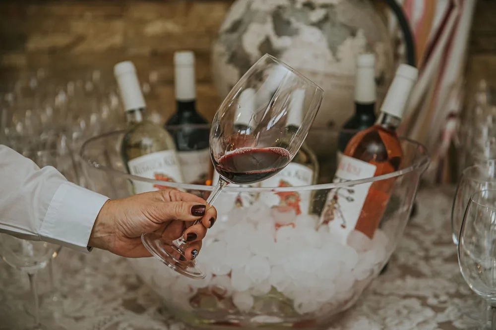 Hand holding a wine glass above a bowl with bottles, perfect for wine tasting themes