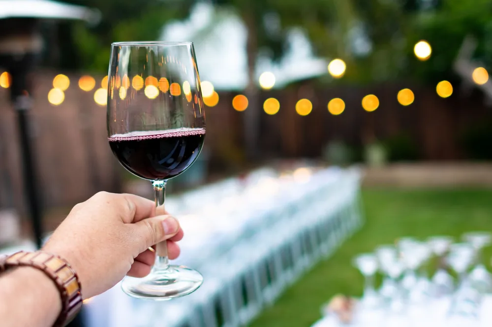 Hand holding wine glass with bokeh lights in outdoor celebration setting
