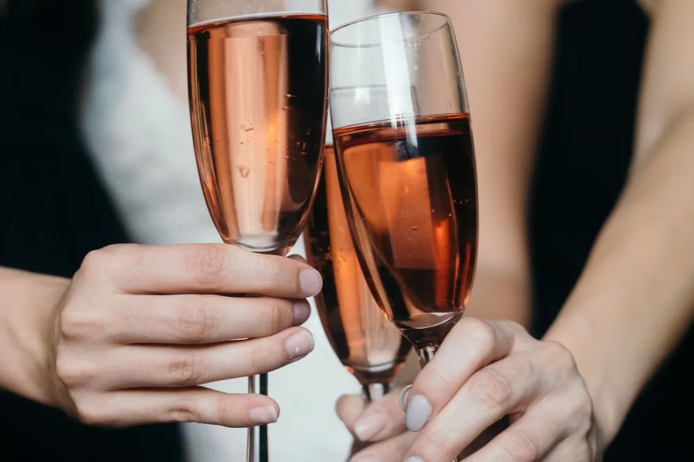 Hands toasting with rose wine glasses, capturing festive spirit