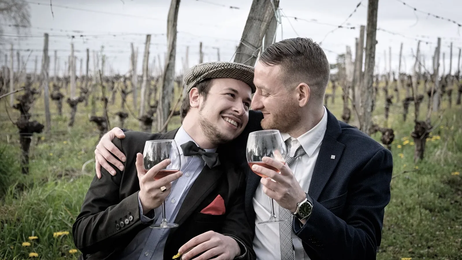 Happy couple in vineyard hugging and sharing a glass of wine, showcasing romance and joy outdoors