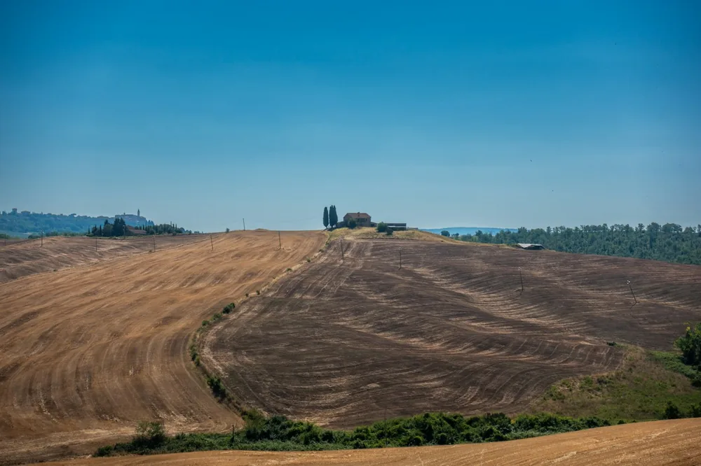 Harvested fields and a distant farm on rolling hills