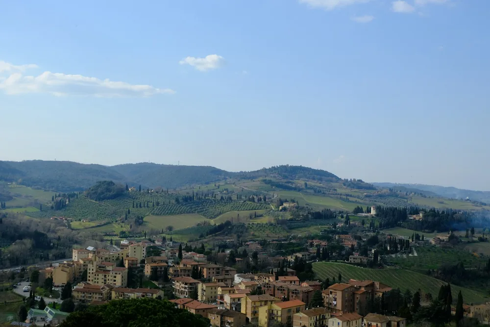 Hillside town with rolling green hills under blue sky