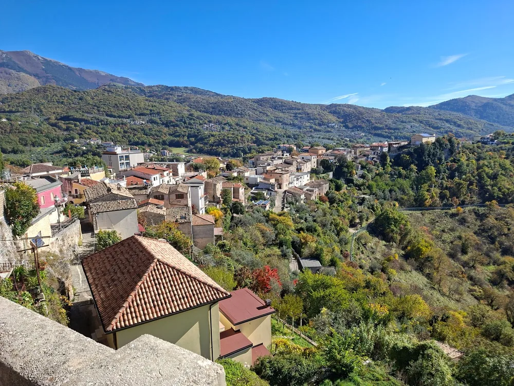 Hillside village with lush greenery and terracotta roofs in a mountainous landscape
