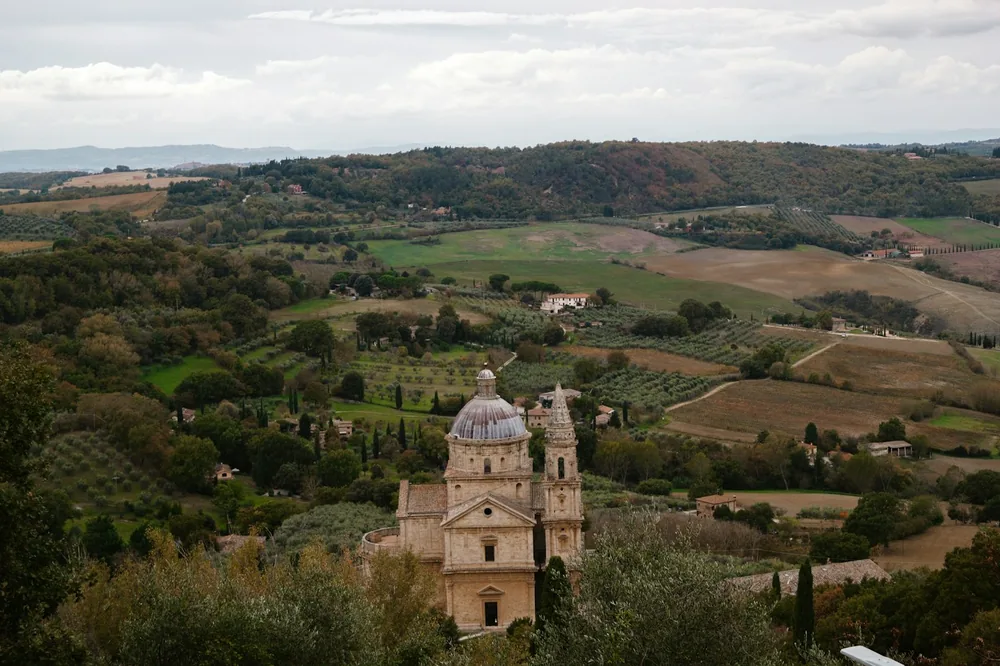 Historic church with domed towers in rolling tuscan landscape