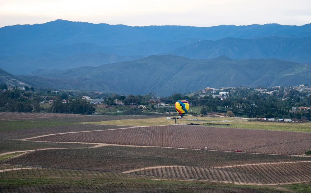 Hot air balloon flies over Temecula's scenic vineyards and mountains