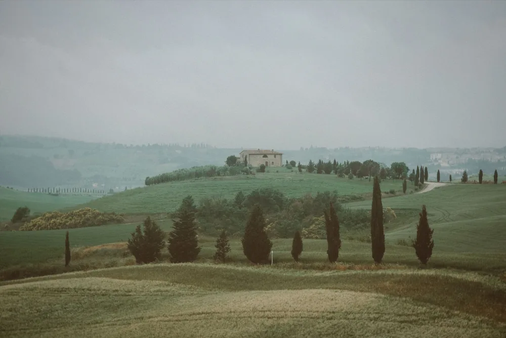 Idyllic Tuscan hills with a farmhouse surrounded by cypress trees in a misty landscape