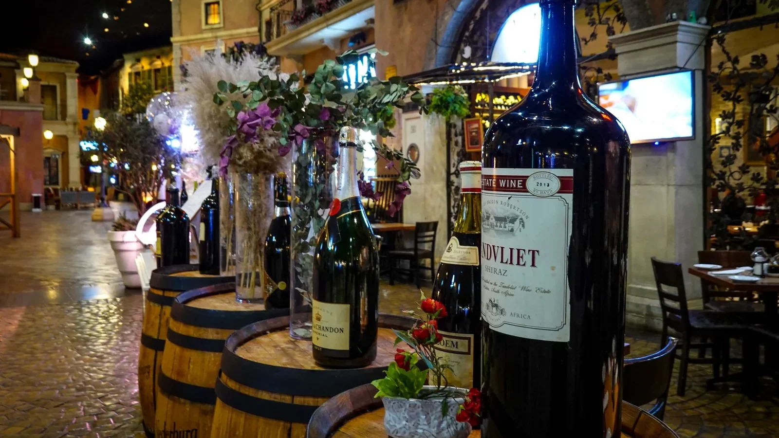 Indoor setting showcasing wine bottles and wooden barrels in a rustic vibe