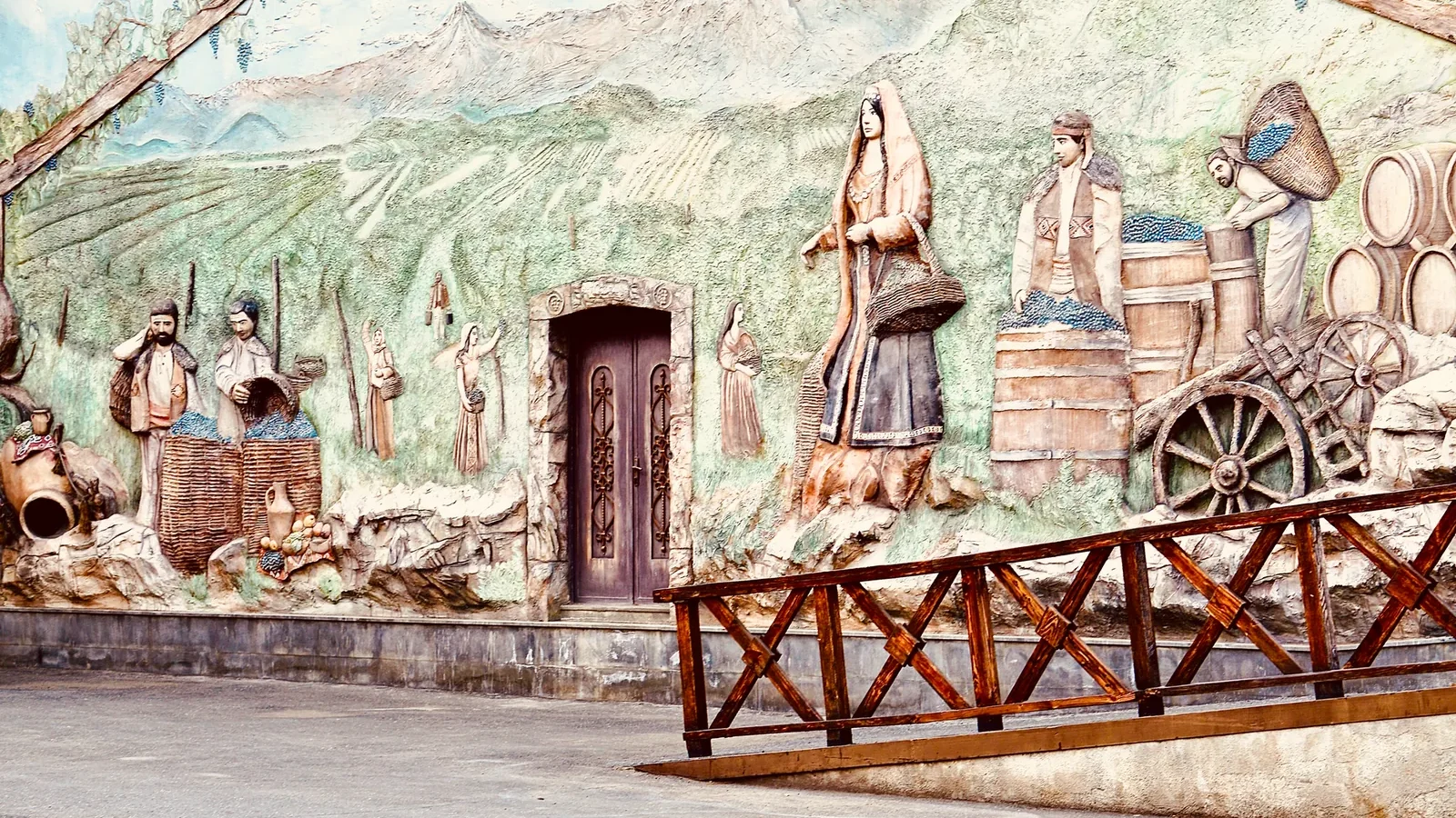 Intricate bas-relief wall art depicting farmers harvesting grapes in a vineyard setting