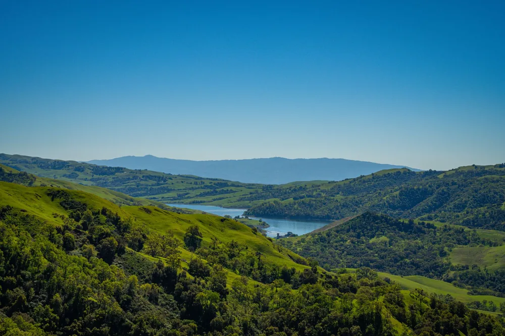 Lush green hills and a tranquil lake in Sunol, California