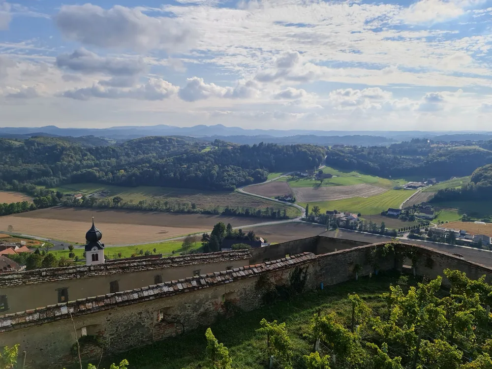 Lush rolling hills and farmland with a small church tower