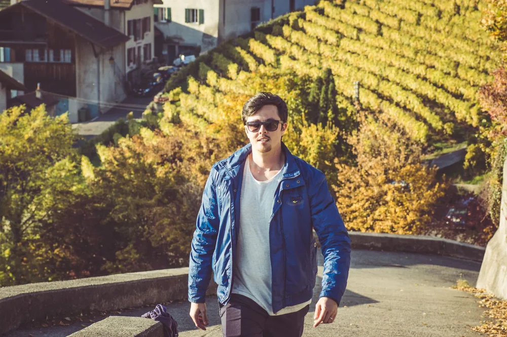 Man in blue jacket walking in vineyard during autumn daylight
