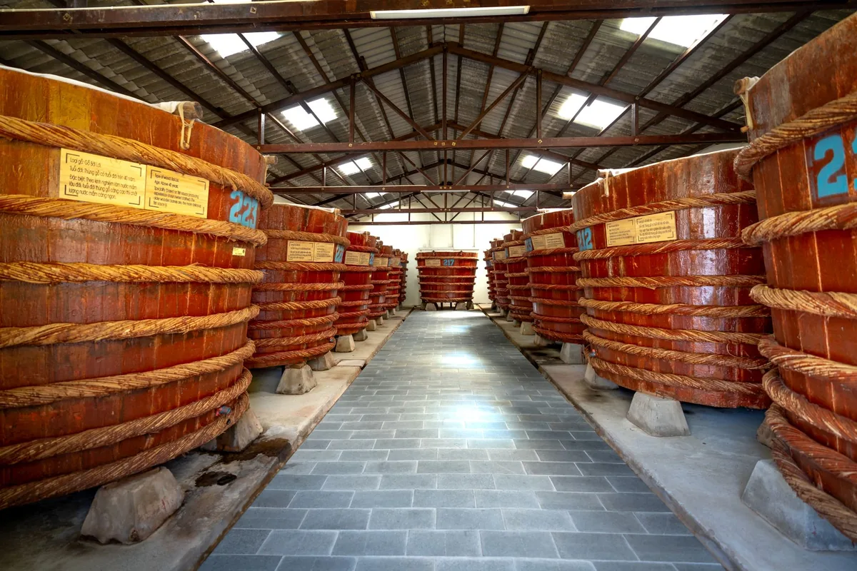 Massive wooden barrels arranged in a distillery's interior storage space