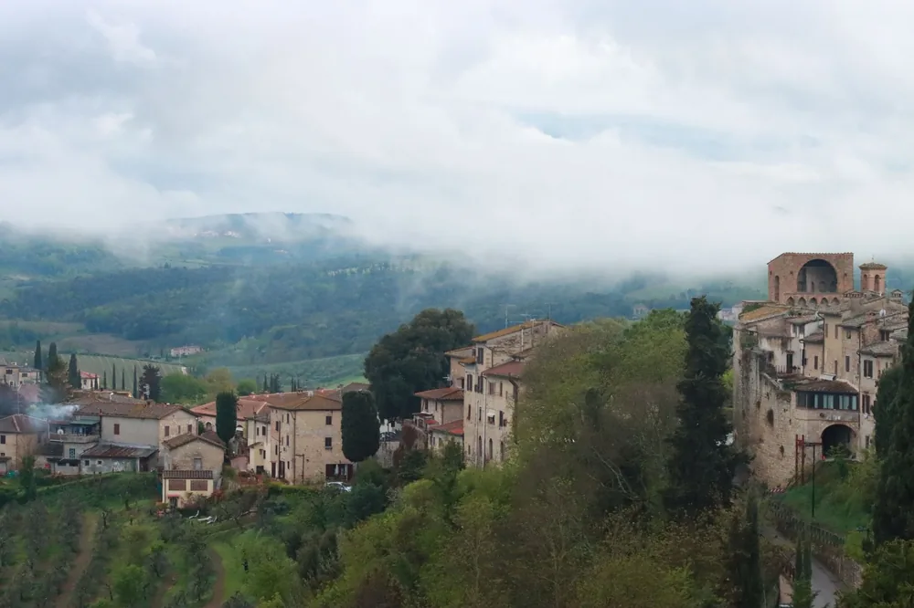 Medieval village with gothic architecture enveloped by mist on lush hillsides