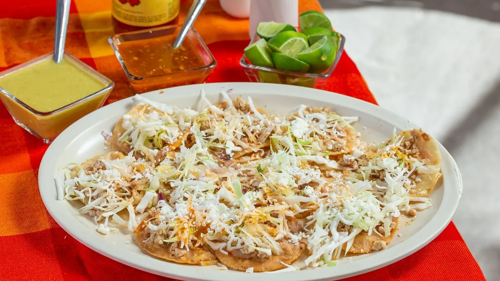 Mexican chilaquiles topped with sauce and cheese, served with fresh limes