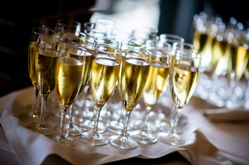 Multiple champagne glasses filled with sparkling wine at an event. Perfect for celebrations and parties
