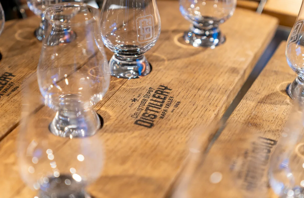 A glass of red wine beside a carved roast on a plain wooden table
