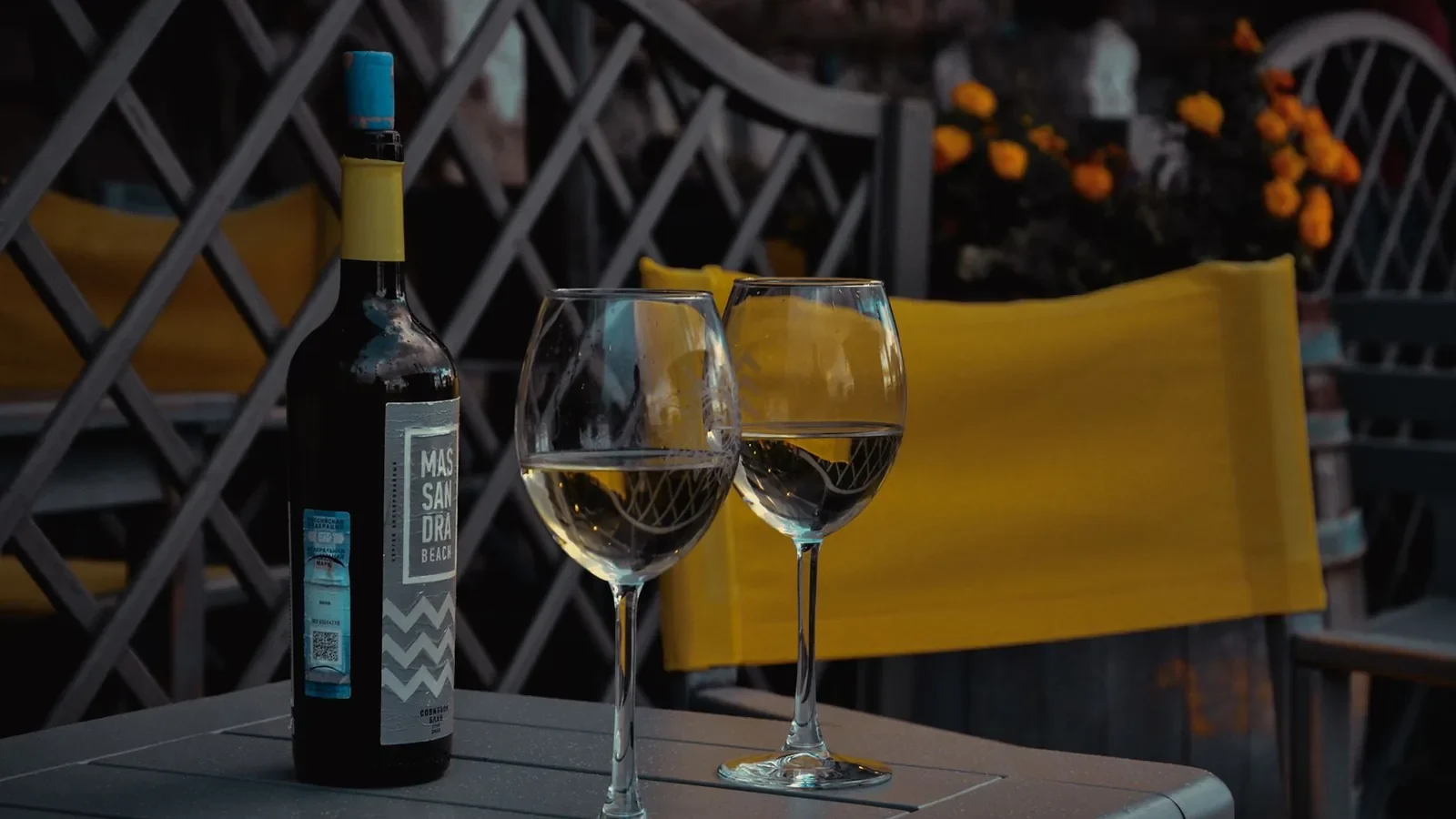 Outdoor setting with two glasses of white wine and a bottle