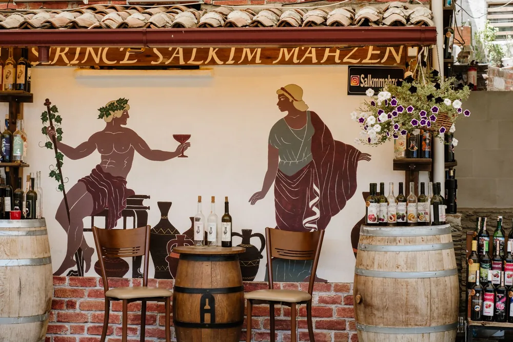 Outdoor wine bar with artistic mural and wooden barrels, perfect for a rustic vibe