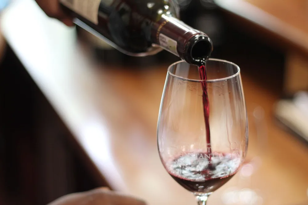Red wine being poured into a glass with a selective focus and blurry background