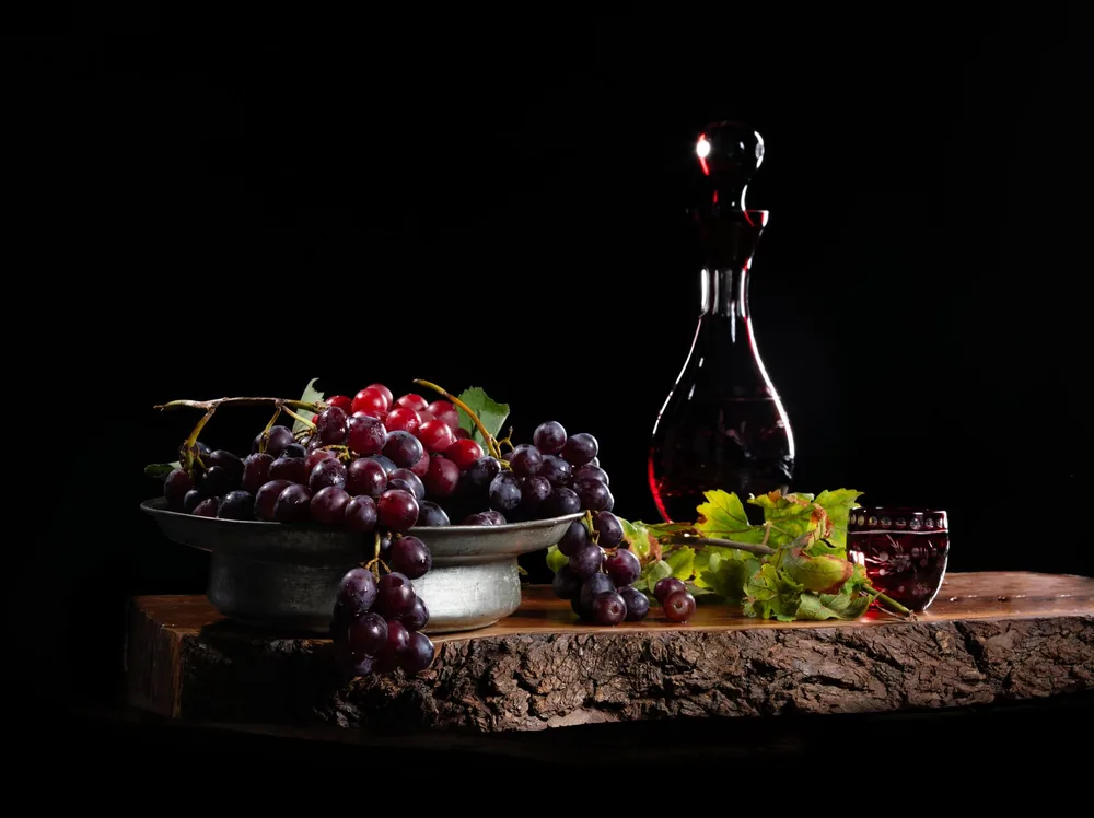Rich still life of grapes and wine decanter on a wooden surface, enhancing elegance and class