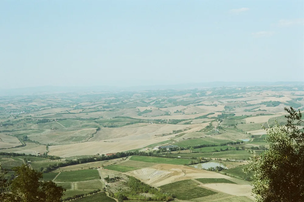 Rolling patchwork fields and vineyards stretch hazily across the Tuscan valley