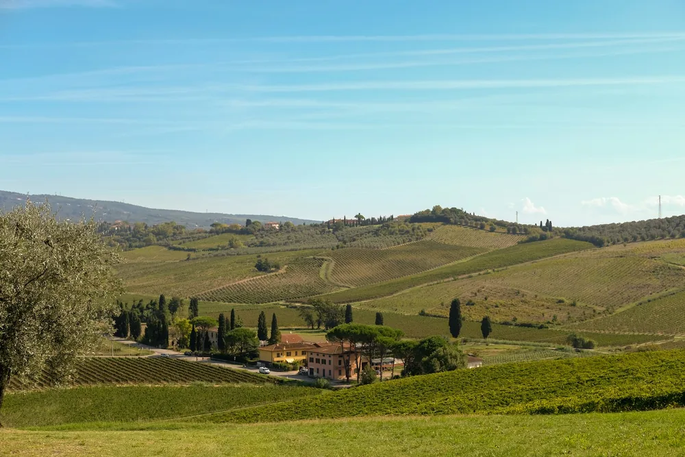 Rolling tuscan hills with vineyards and a villa