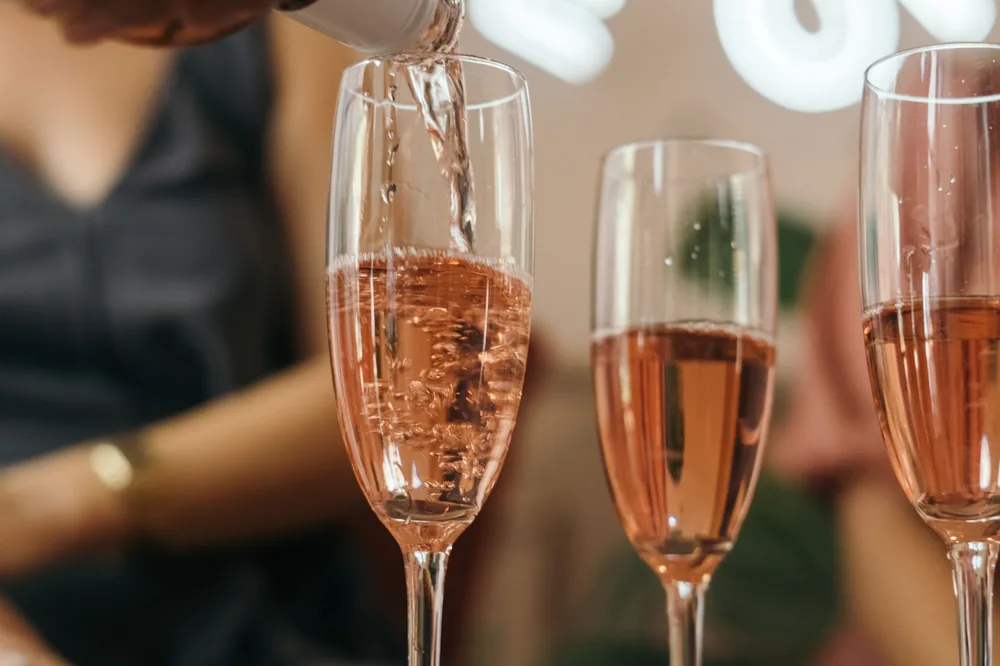 Rosé wine being poured into elegant champagne flutes during a celebration
