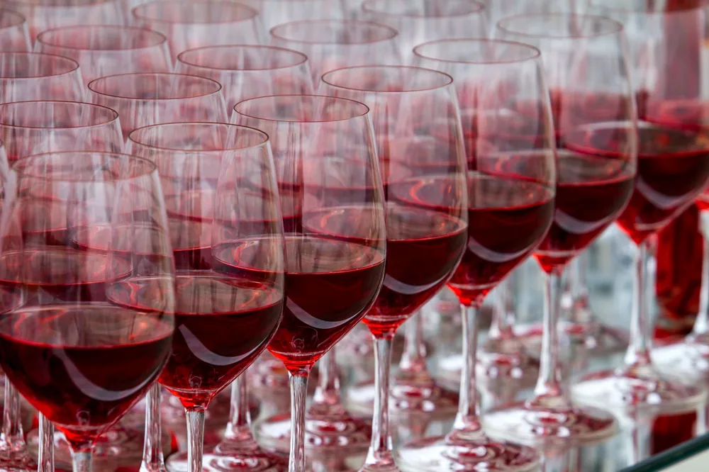 Rows of red wine glasses filled with red liquid, creating an elegant arrangement