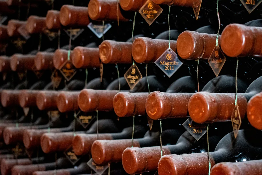 Rows of vintage 2011 wine bottles stored horizontally in a dimly lit cellar