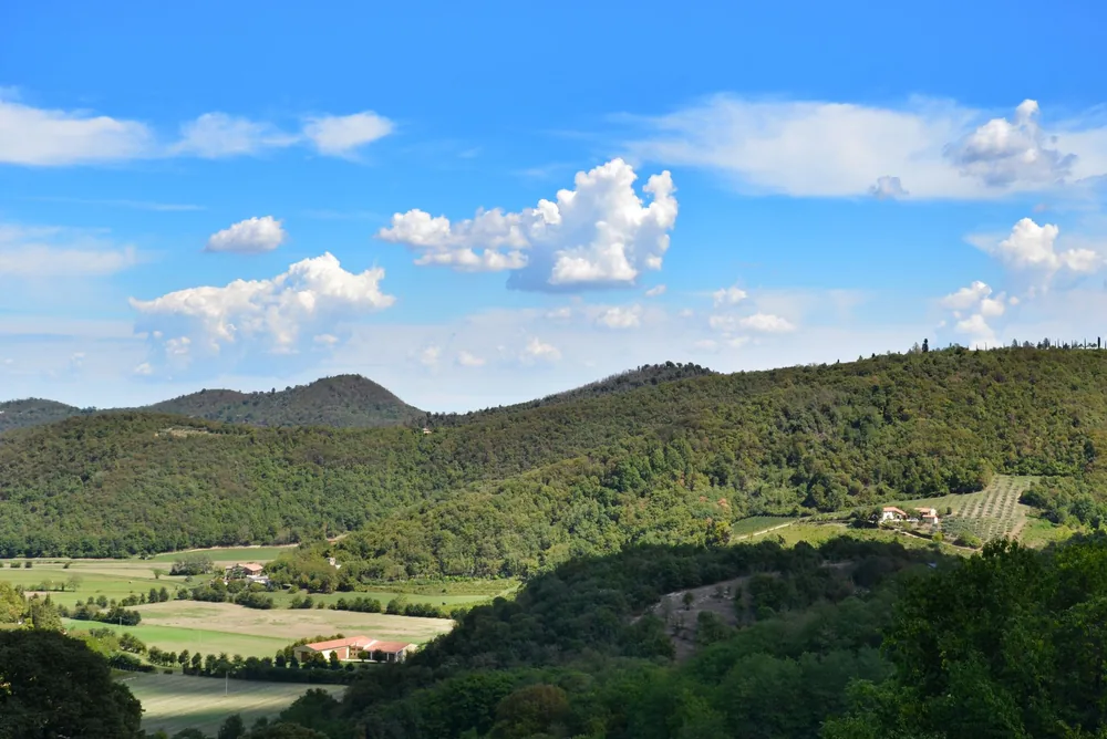 Rural landscape with lush green hills and blue sky, highlighting nature's tranquility