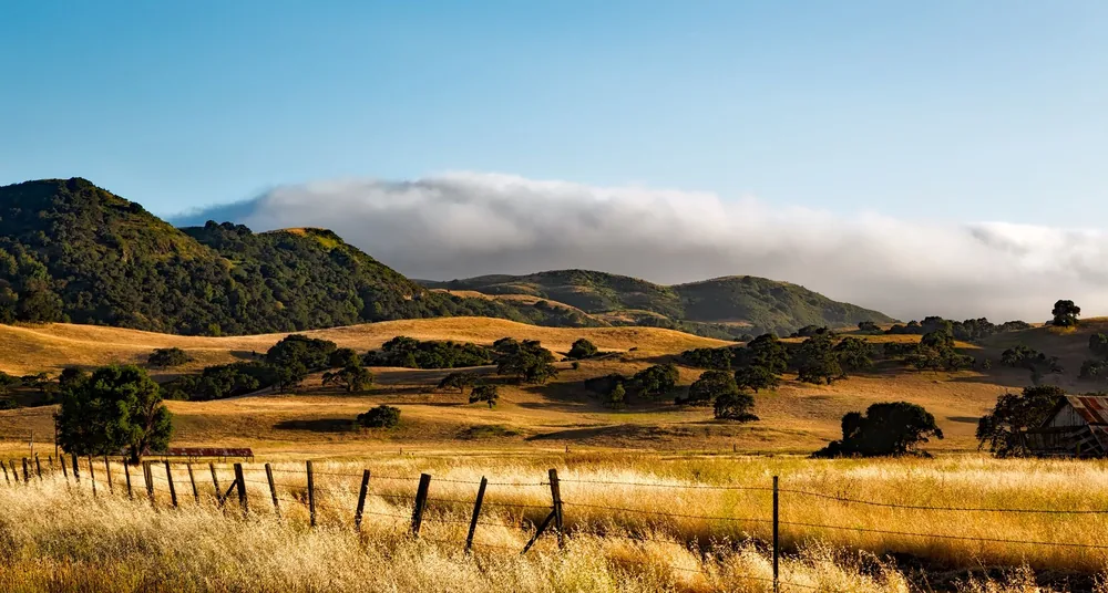 Rural landscape with rolling hills, fields, and a clear blue sky