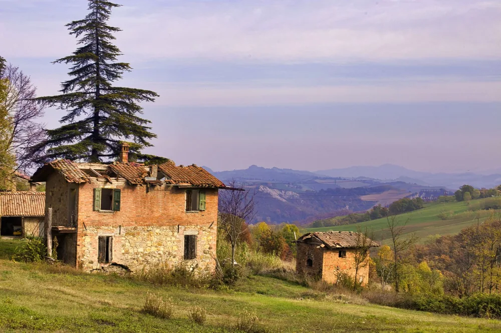 Rustic abandoned brick house surrounded by scenic countryside views and hills