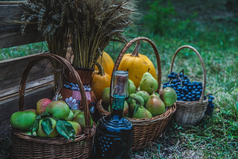 Rustic autumn display featuring baskets of apples, pears, grapes, and pumpkins outdoors