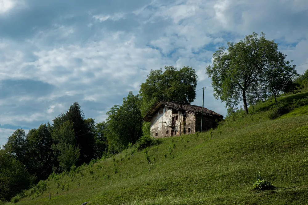 Rustic house nestled in a lush green countryside, under a cloudy sky