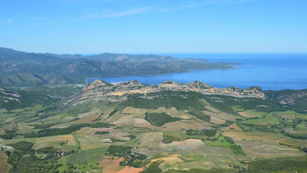 Spectacular aerial view showcasing coastal hills and agricultural fields under a clear sky