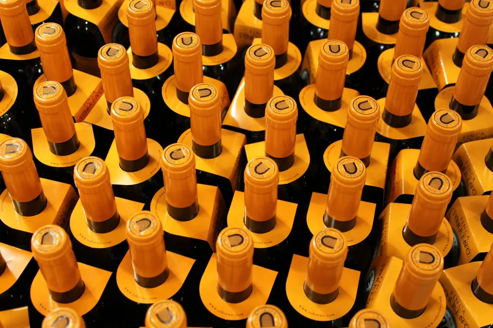 Stacked wine bottles with yellow corks in an indoor cellar setting