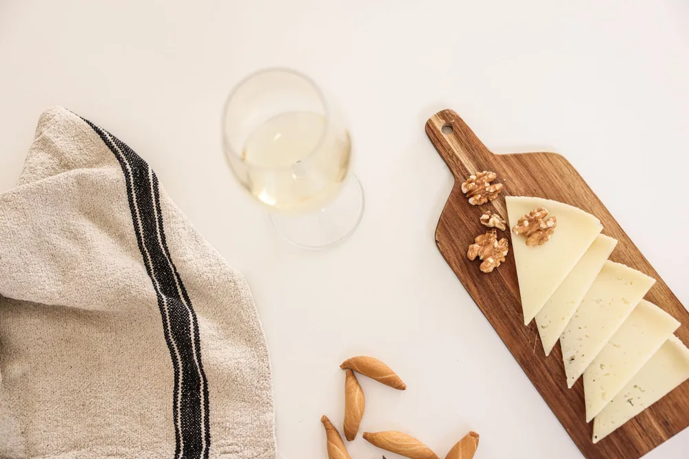 Still life with cheese, walnuts, and wine on a wooden board