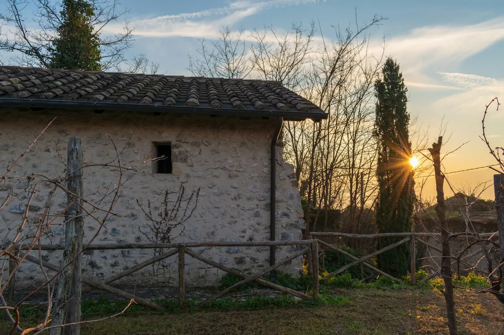 Stone building with sunset behind trees