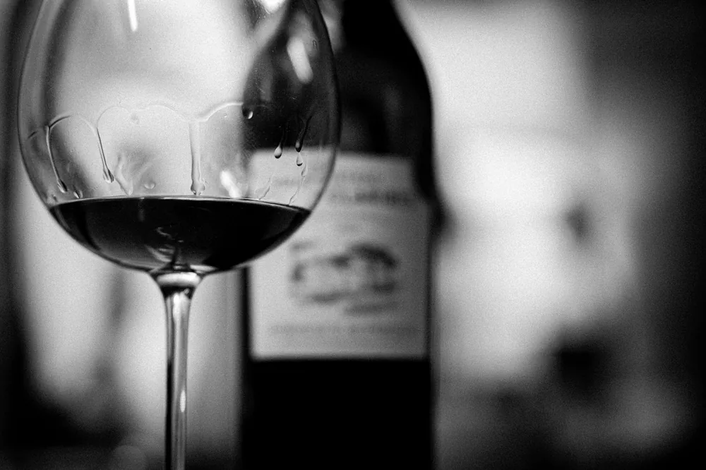 Stylish black and white photo of a wine glass and bottle in focus. Perfect for elegant settings