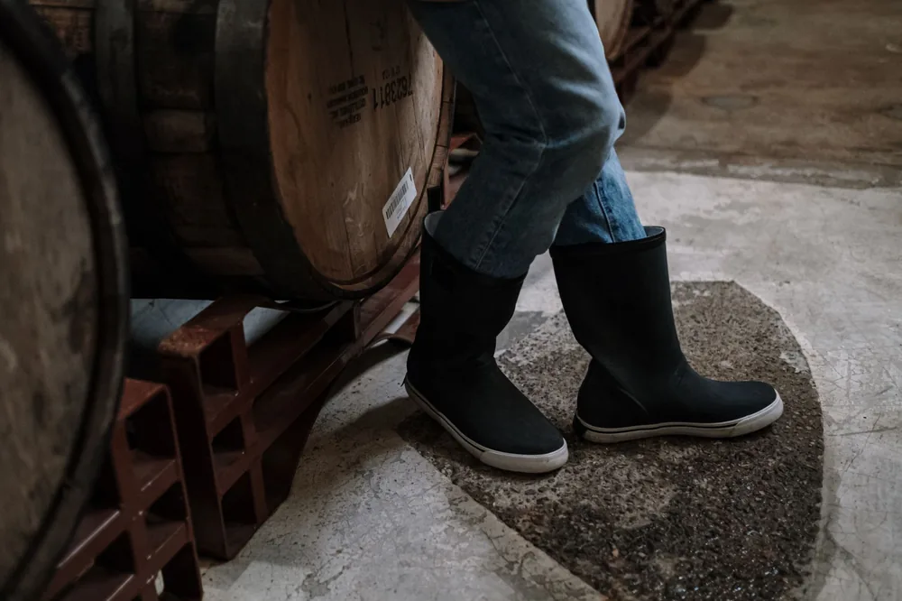 Stylish black boots paired with jeans in a rustic wine cellar, perfect for fashion and lifestyle themes