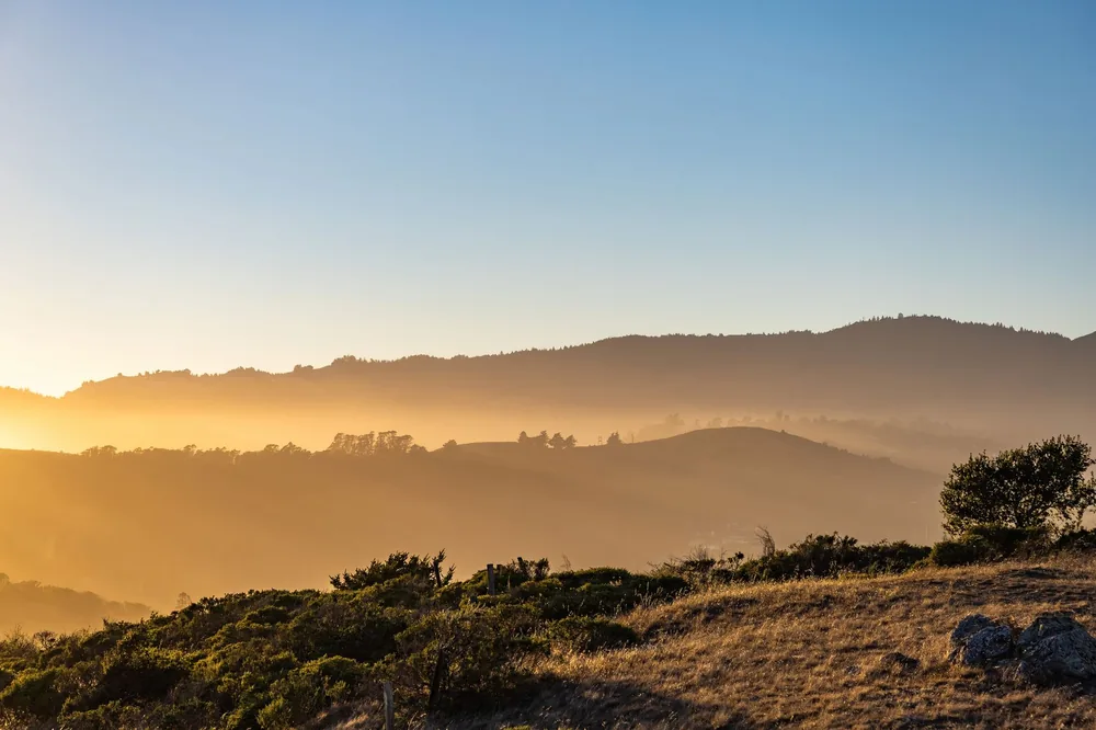 Sunset view depicting vivid golden hour colors over expansive hills and clear sky