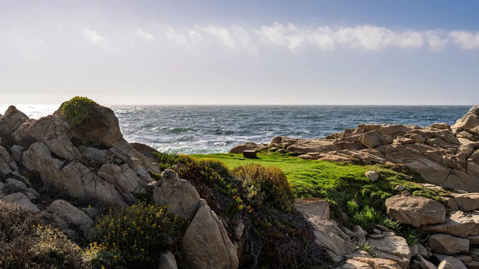 The rocky coastline and ocean in Monterey, California under a bright sky