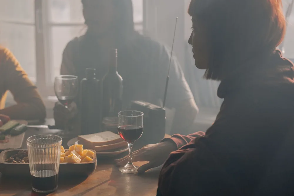 Three friends enjoying wine and snacks in a cozy indoor setting, highlighting companionship