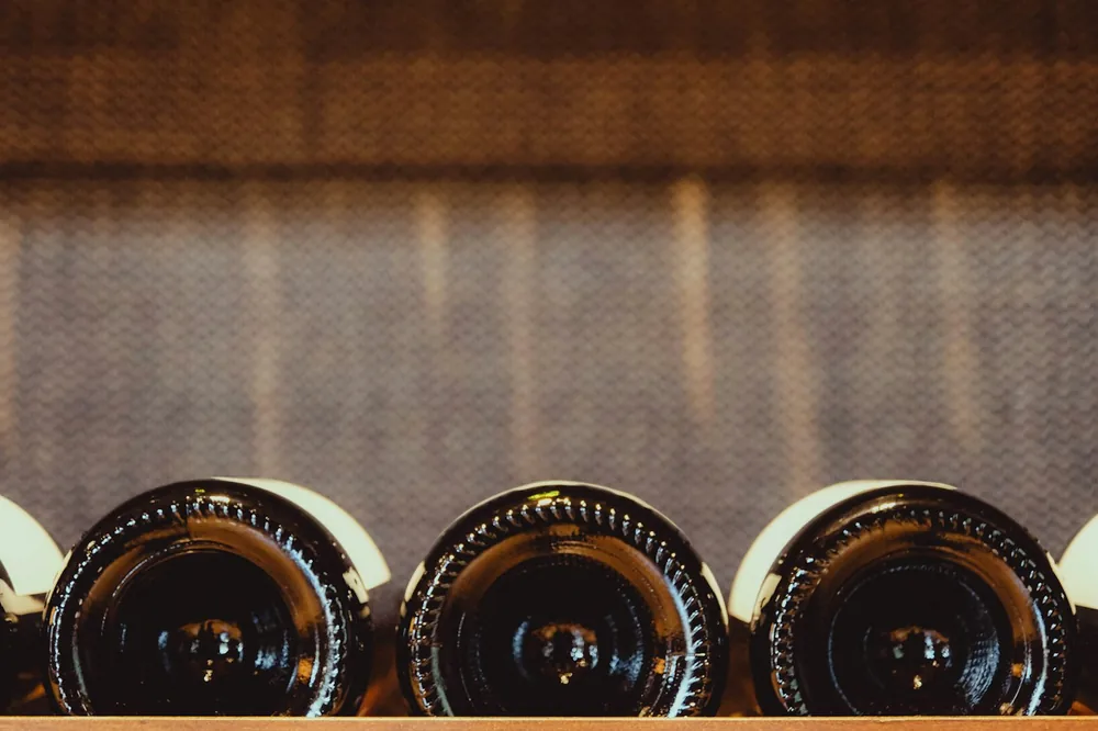 Three wine bottles lined up on a shelf