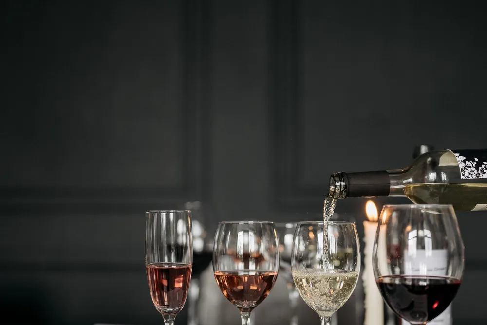 Three wine glasses with red, white, and rosé wine on a dimly lit table setting