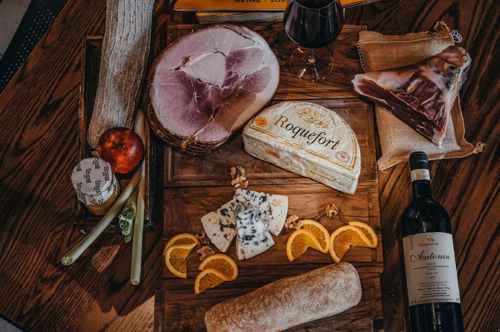 Top view of a gourmet charcuterie board with wine, cheese, and cured meats on a rustic wooden table